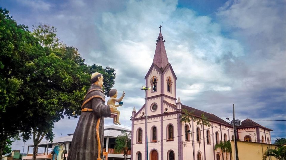 Foto da Praça Santo Antônio em Oriximiná, com a estatua de Santo Antônio em primeiro plano e igreja ao fundo.